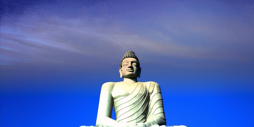 A picture of a tall Buddha statue in Amravati with a clear blue sky in the background