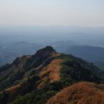 A bird’s eye view of green-capped majestic peaks surrounded by misty blanket of air.