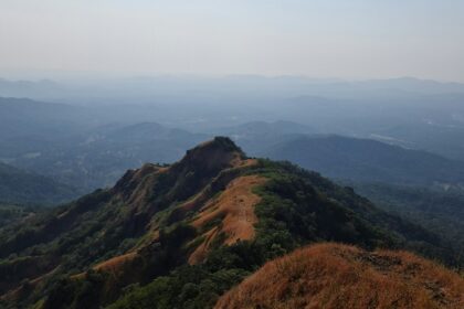 A bird’s eye view of green-capped majestic peaks surrounded by misty blanket of air.