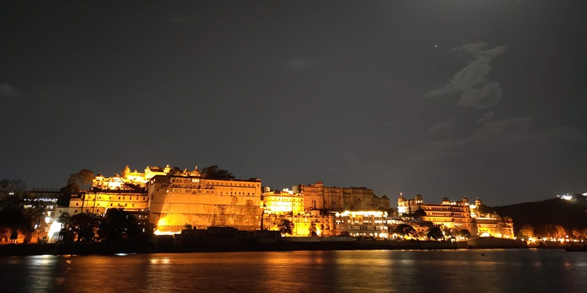 A nighttime view of a ghat around a lake near Sajjangarh Wildlife Sanctuary