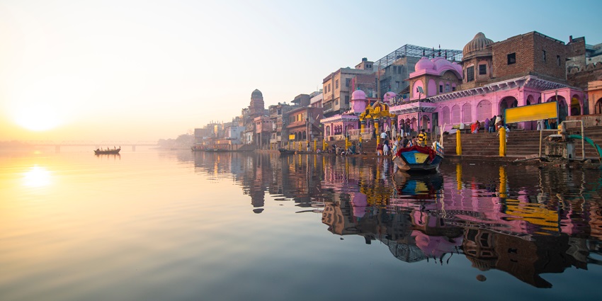 View of a temple ghat in India, adorned with intricate carvings and surrounded by lush greenery.