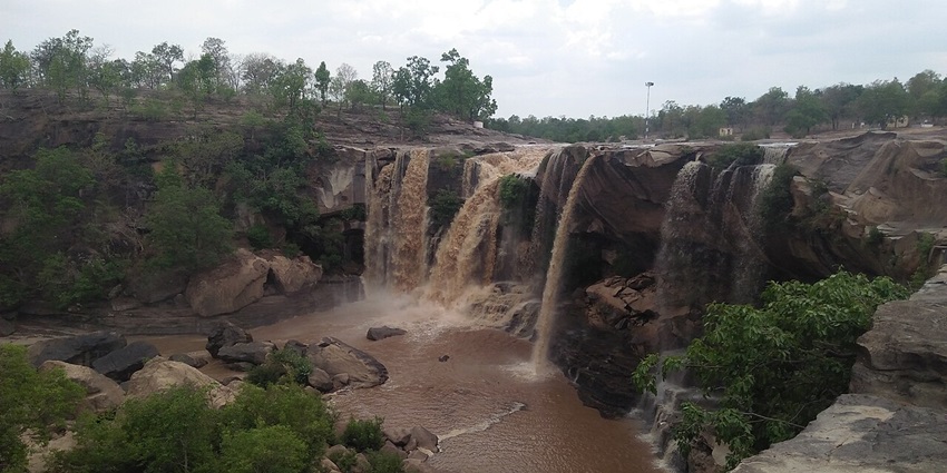 Cascading water tumbling over rocky terrain, surrounded by lush greenery.