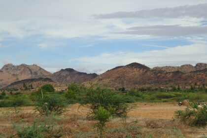 A picture of a couple of hills taken from a distance with green valleys surrounding the hills