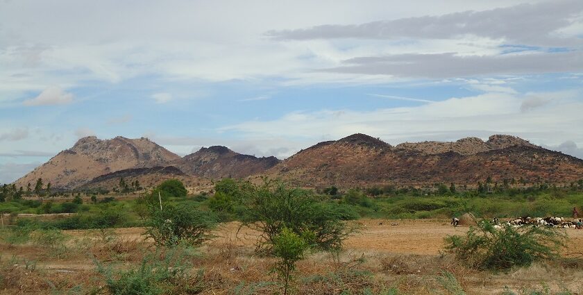 A picture of a couple of hills taken from a distance with green valleys surrounding the hills