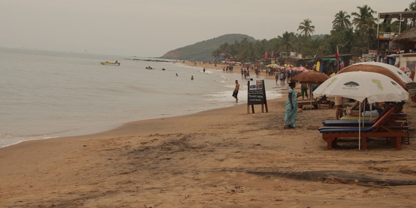 Rocky shoreline and waves crashing at scenic Anjuna Beach in Goa, India.