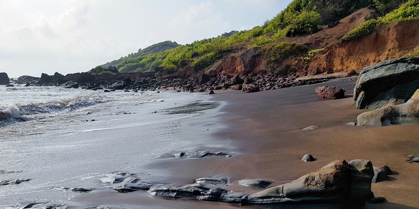 A view of shoreline with rocks at Anjuna Beach, one of the top places to visit in Anjuna.