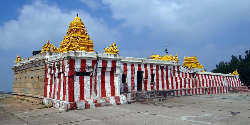 A magnificent Hindu temple among Shiva temples in Nepal with a golden gopuram and red and white striped walls.
