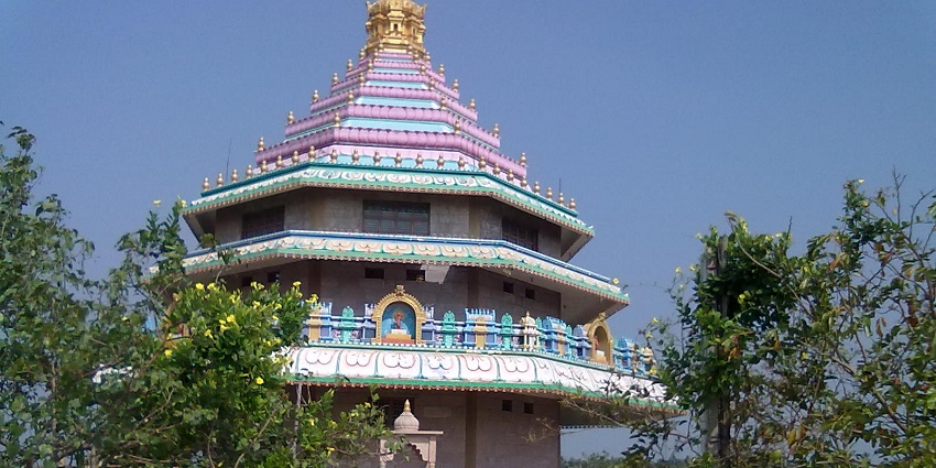 View of Antarvedi temple, its colorful walls and roof carved with details, standing amidst lush greenery