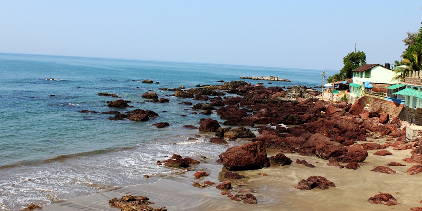 A scenic view of the pristine Arambol Beach in Goa with turquoise waters and a rocky shore