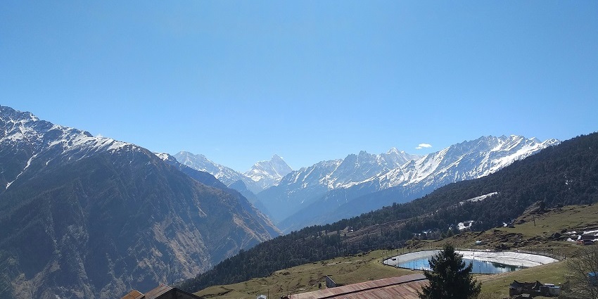 Scenic view of Auli showcasing snow-capped mountains and lush green valleys.