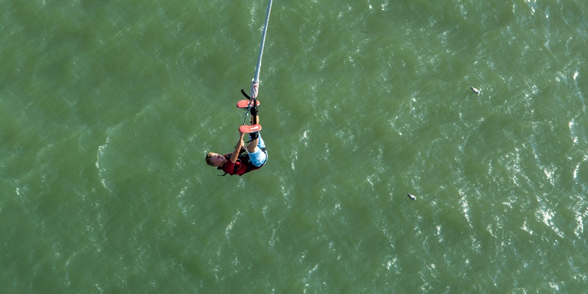 Man falling into the ocean, captured mid-air enjoying best bungee jumping in Pokhara.