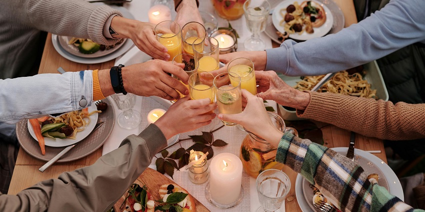 Six people with drinks in their hands clinking their glasses for a 'cheer!'
