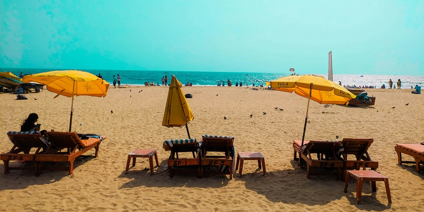 A glimpse of people sunbathing at the Baga Beach surrounded by sands and azure waters.