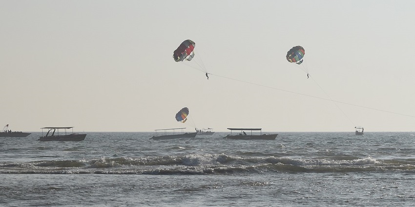 A picture of a beach near Arambol with visitors enjoying parasailing