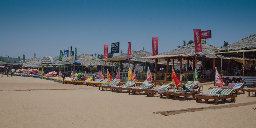 A scenic view of the Baga Beach featuring pristine golden sands dotted with shacks.