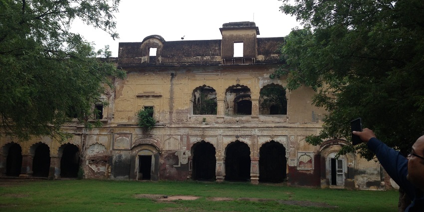 A picture of a frontal view of a fort hiding behind trees, taken on a sunny day
