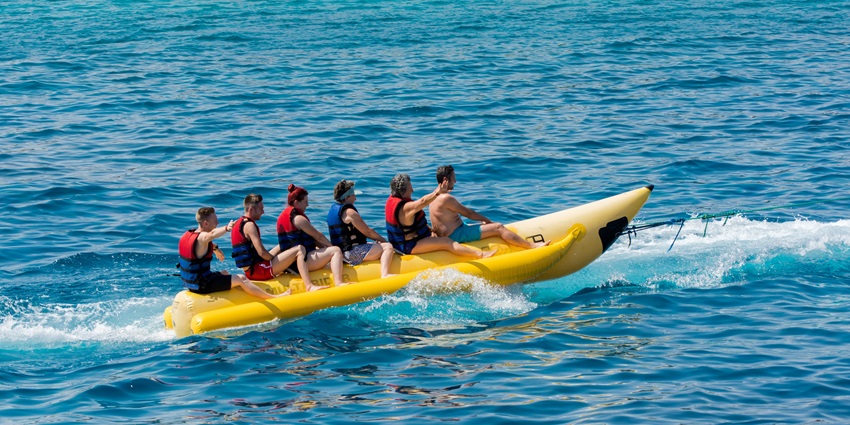 View of a group of people sitting on a long banana boat amidst the sea