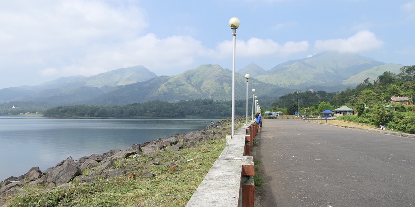 A picture of a road moving parallel a water body with mountains at a distance