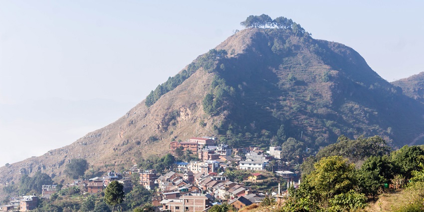 A picture of a town with a hill in the background, in Nepal which is one of the best places to visit in June