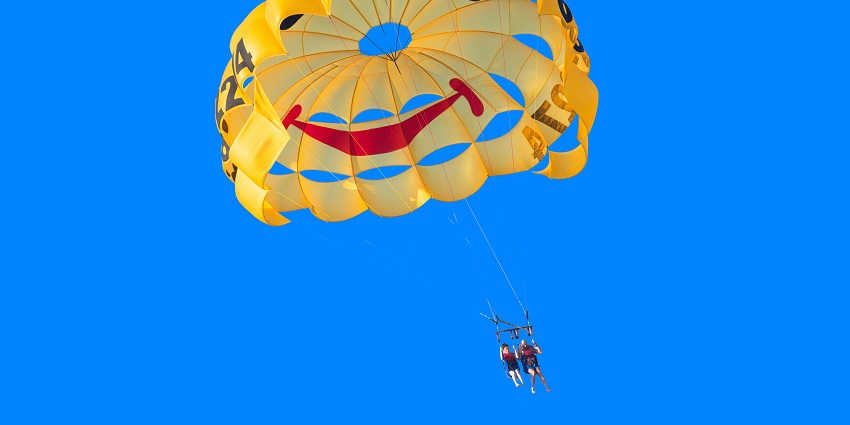 An image of two people skydiving in Thailand with a red and yellow sky under the blue sky.