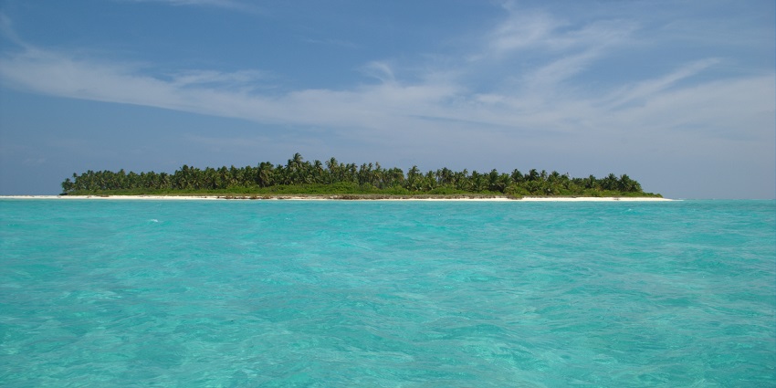 Distant view of the crystal waters and an island far away covered with lush trees