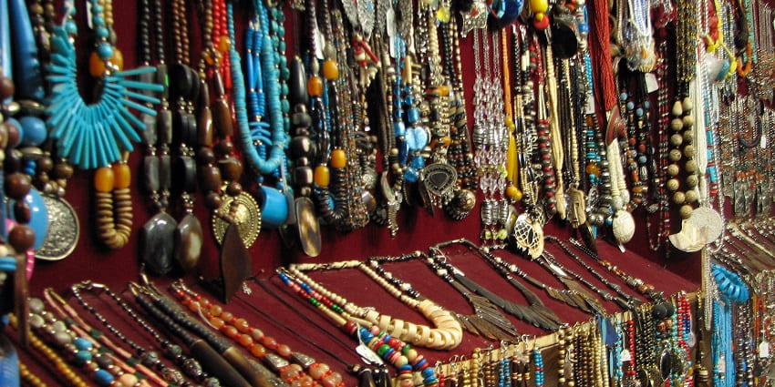 Bustling Jaipur market with vibrant stalls, colourful textiles, and people shopping.