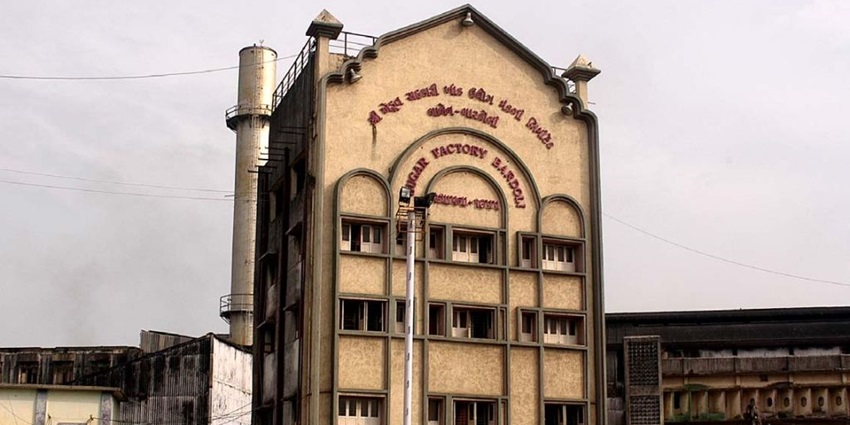 View of the Bardoli sugar factory complex with large industrial buildings and surrounding