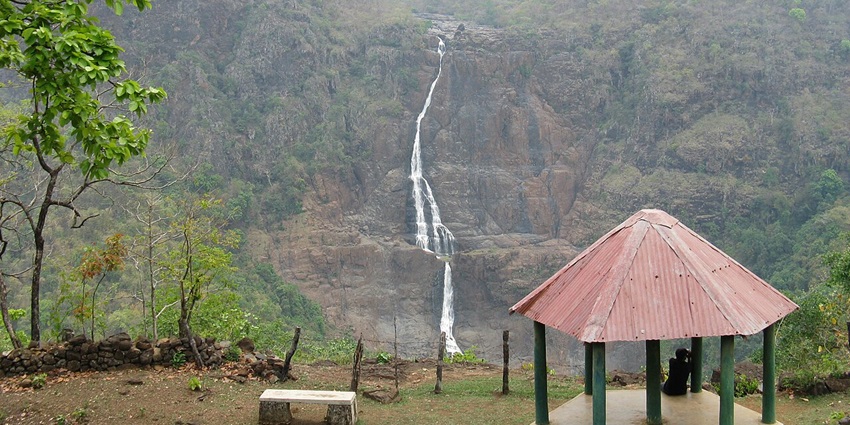 Barehipani Falls in Odisha, displaying a tall waterfall cascading down rugged cliffs amidst lush green forest.