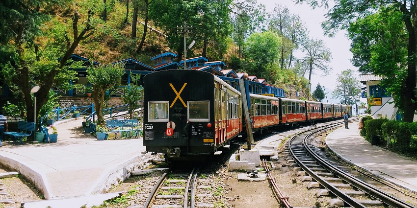 Image of black and red train on train tracks in the forest - Barog is one of the best hill stations near Chandigarh