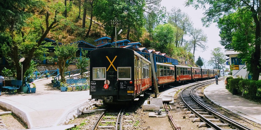 Image of black and red train on the tracks moving through the mountains in Barog