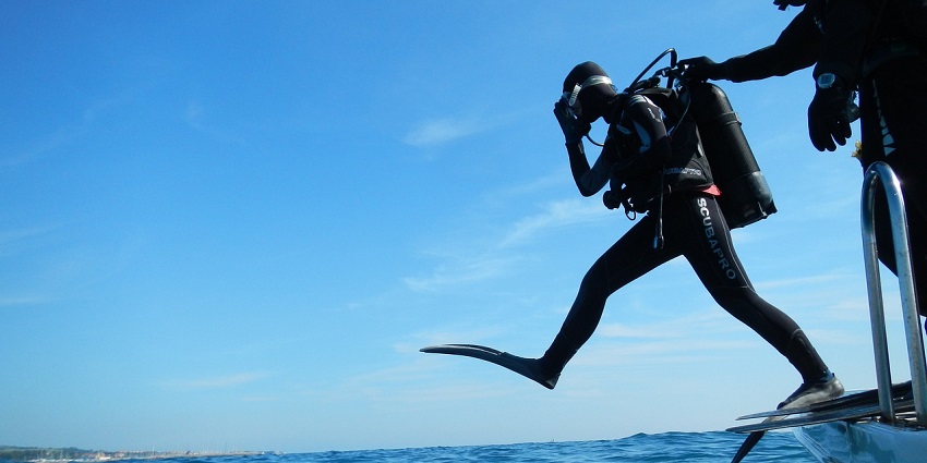 A scuba diver taking a giant stride into the water, ready to explore the underwater world.