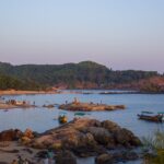 The beaches near Belgaum are surrounded by dense forests and rocky hills, featuring traditional fishing boats.