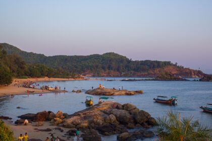 The beaches near Belgaum are surrounded by dense forests and rocky hills, featuring traditional fishing boats.