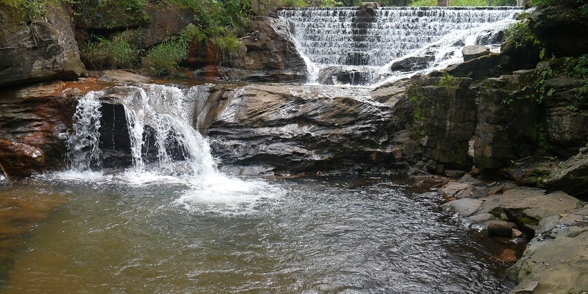 A scenic view of Bee Falls, featuring cascading water amidst lush greenery and natural surroundings