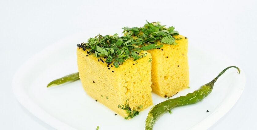 A mouth-watering view of a plate served with yellow dhokla garnished with coriander.