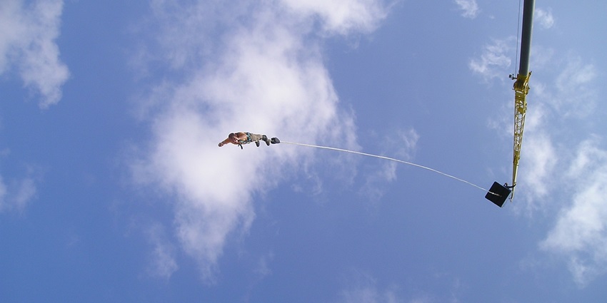 A person bungee jumping against a vibrant sunset contrasting against the warm sky.