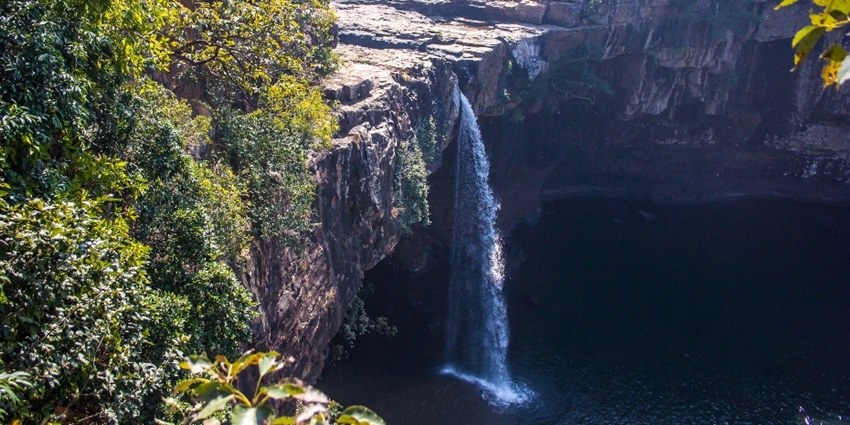 Waterfalls cascading down rocky cliffs, surrounded by lush greenery.