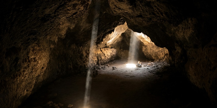 Light streaming into a dark cave, illuminating the rocky interior and creating a dramatic effect