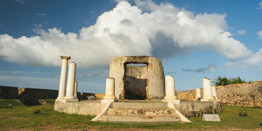Image of ancient fort ruins on a green field under clear blue sky and beautiful clouds