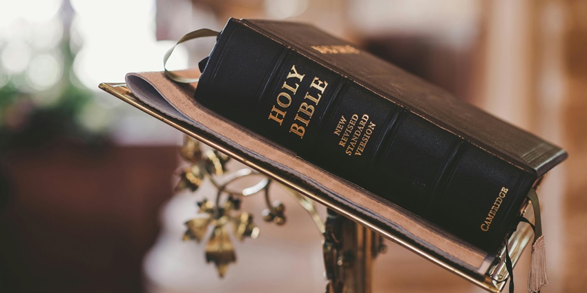 Holy Bible on a wooden stand, opened and placed in a dimly lit room for reading