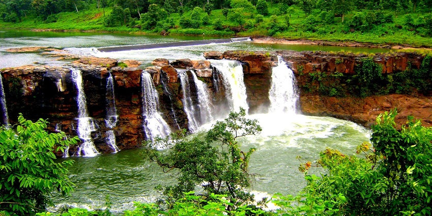 A stunning waterfall with multiple streams cascading over rocks, surrounded by nature.