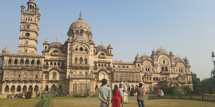 People admiring the grand Laxmi Vilas Palace, home to the Maharaja Fateh Singh Museum.