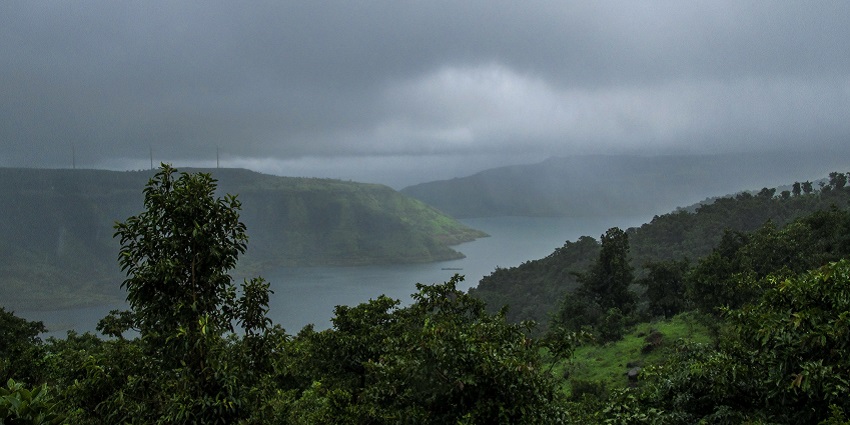 A picture of a picturesque landscape with hills and greenery under dense clouds