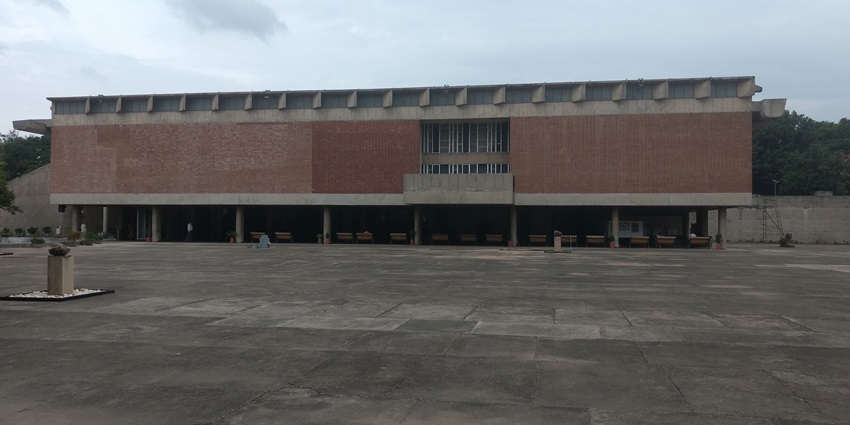A picture of a red building taken from outside with trees visible in the background