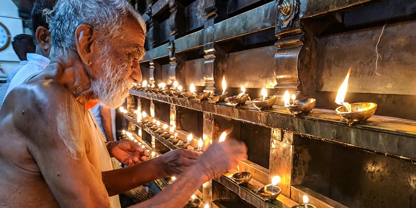 Old man lighting diya in the premises of Galtaji Temple.
