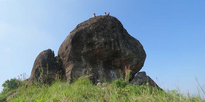 View of a large rock standing amidst emerald landscapes of the trek