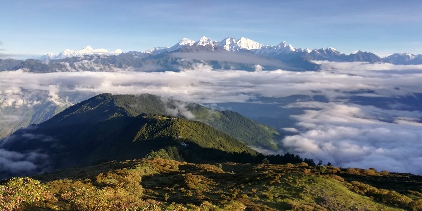 Scenic view of lush green hills and terraced fields in Nepal under a clear sky.