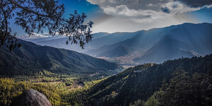 Stunning sunset over the mountains and forests of Bhutan, highlighting natural beauty.