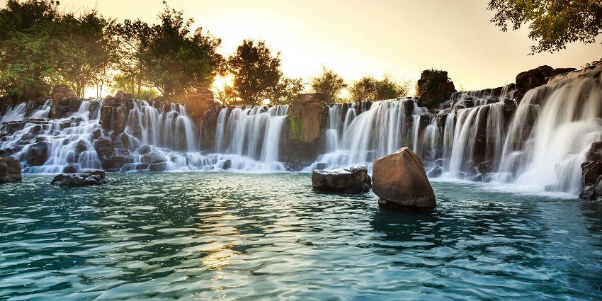 A picture of a beautiful pond of water formed under a waterfall