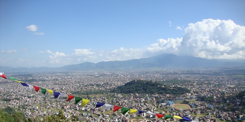 Panoramic view of a valley decked with hills, terraced fields, and scattered buildings.
